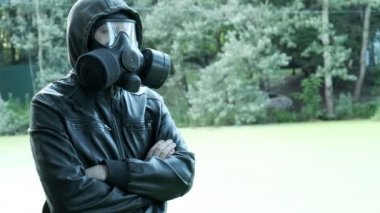 Gaz maskeli adam zehirli su deposunun yanında. Kimyasal silah koruması, virüs salgını