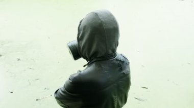 Gaz maskeli adam zehirli su deposunun yanında. Kimyasal silah koruması, virüs salgını