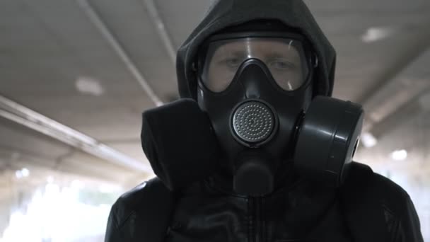 Uomo in maschera antigas, giacca nera con cappuccio passeggiante per lungo tunnel, sottopassaggio — Video Stock