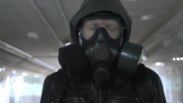 Uomo in maschera antigas, giacca nera con cappuccio passeggiante per lungo tunnel, sottopassaggio — Video Stock