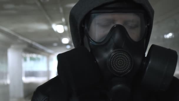 Mężczyzna w masce gazowej, czarna kurtka z kapturem przechodzącym przez długi tunel, przejście podziemne — Wideo stockowe