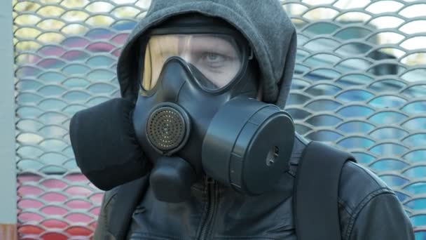 Hombre en máscara de gas, chaqueta con capucha de pie al aire libre delante del tren en movimiento — Vídeos de Stock