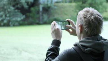 Adam akıllı telefonlu ördeklerin fotoğraflarını çekiyor. Kuşların vahşi yaşam fotoğraflarını çekmek