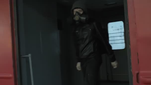 Extraño hombre en máscara de gas, chaqueta con capucha se baja del tren a la plataforma del ferrocarril — Vídeo de stock