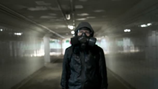 头戴防毒面具的男子,黑色夹克,头罩立在长隧道中,地下通道 — 图库视频影像
