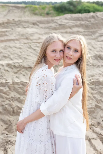 Două surori tinere gemene atractive care pozează la cariera de nisip în haine albe elegante — Fotografie, imagine de stoc