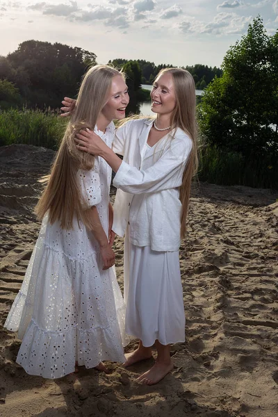 Deux jumeaux aux longs cheveux blonds s'amusent à la plage de sable en vêtements blancs élégants — Photo