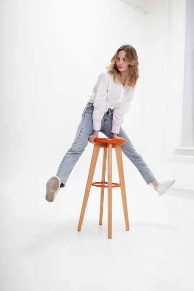 Jovem bonito sorridente caucasiano menina posando em camisa branca, jeans azul no estúdio — Fotografia de Stock