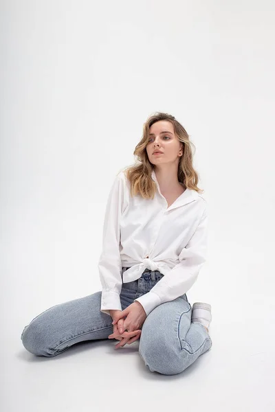 Jong schattig pensive Kaukasisch meisje poseren in wit shirt, blauwe jeans in de studio — Stockfoto