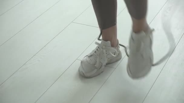Detailní záběr ženských nohou v teniskách skákání ve vzduchu při použití švihadla — Stock video