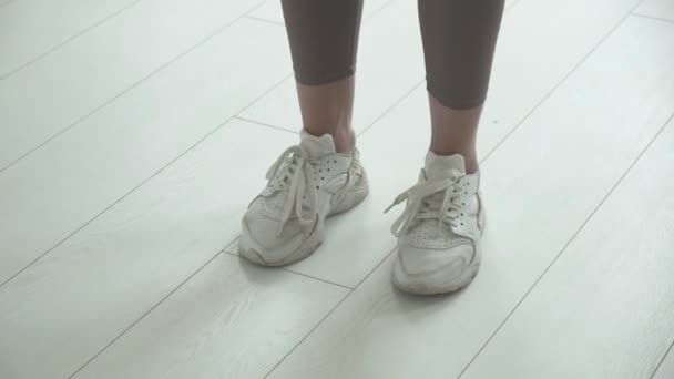 Gros plan des pieds féminins en baskets sautant dans l'air tout en utilisant une corde à sauter — Video