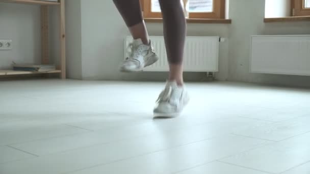 Primo piano di piedi femminili in scarpe da ginnastica che saltano in aria durante l'utilizzo di corda da salto — Video Stock