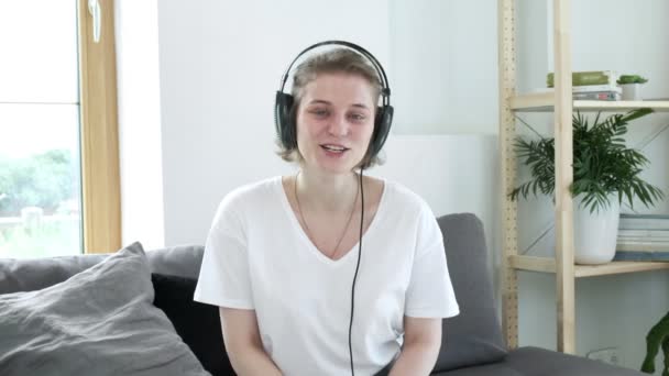 Happy female blogger sits on sofa, speaks to webcam, makes video conference call — Stock Video
