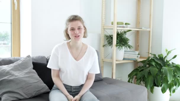 Glad kvinnlig bloggare sitter på soffan, pratar med webcam. videokonferenssamtal — Stockvideo