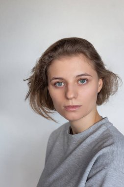 Siyah arka planda kısa saçlı, tişörtlü güzel bir kadının portresi.