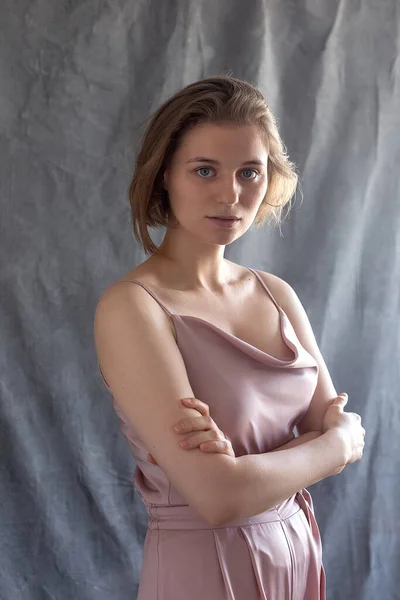 Caucasian woman with short hair in pink suit posing in studio with arms crossed — Stock Photo, Image