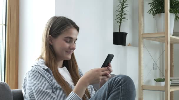 Menina usando telefone inteligente, navegar nas redes sociais na internet, mensagens de texto para casa — Vídeo de Stock