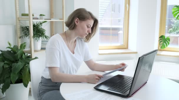 Mädchen überprüft Dokumente, findet Fehler, wirft zerknülltes Papier wütend in Laptop — Stockvideo