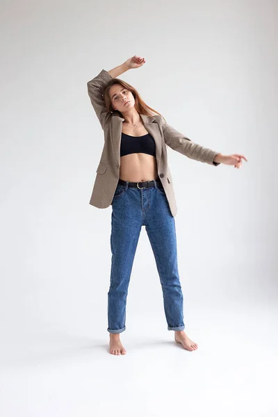 Jeune femme caucasienne en haut noir, jeans bleus et veste costume isolé sur blanc — Photo