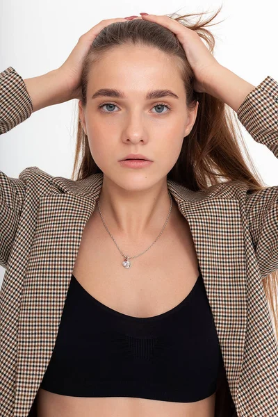 Beyaz arka planda siyah bluzlu ve takım elbiseli genç beyaz kadın.