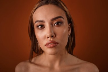 Akşam makyajlı, çıplak omuzlu, küpeli güzel Asyalı kız kameraya bakıyor.