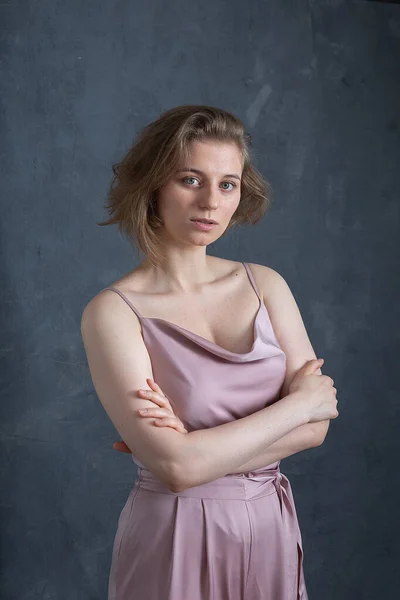 Caucasian woman with short hair in pink suit posing in studio with arms crossed — Stock Photo, Image
