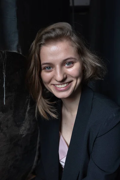 Portrait of pretty woman with short hair posing in jacket on black background — Stock Photo, Image