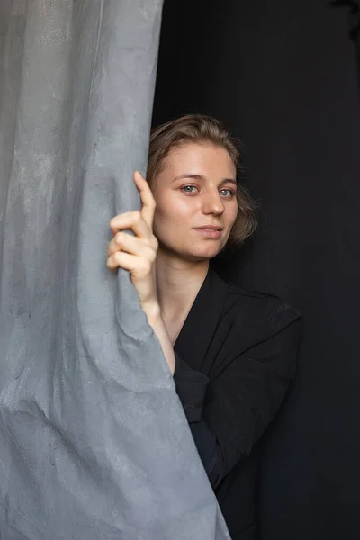 Kaukasische Frau mit kurzen Haaren posiert in schwarzer Anzugjacke und hält Vorhang — Stockfoto