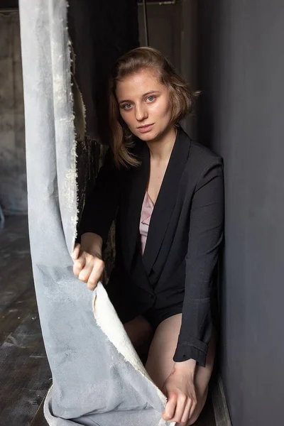 Mulher caucasiana com cabelo curto posando em casaco de terno preto, segurando cortina — Fotografia de Stock