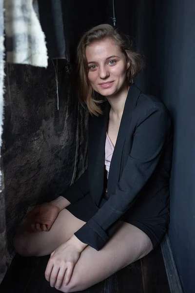 Caucasian woman with short hair poses in black suit jacket, sits on her knees — Stock Photo, Image