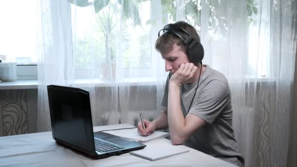 ชายหนุ่มเรียนที่บ้าน เขียนบันทึก การศึกษาออนไลน์ที่แล็ปท็อป งานระยะไกล — วีดีโอสต็อก