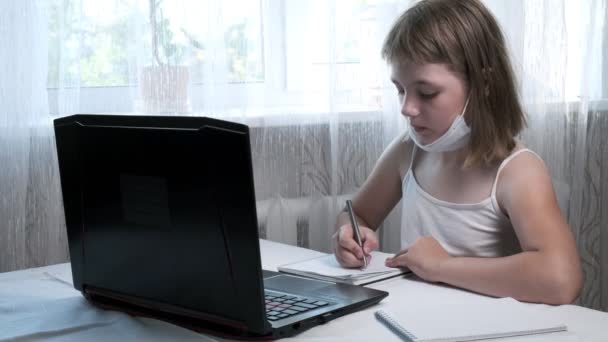 เด็กผู้หญิงในหน้ากากป้องกันศึกษาที่บ้านกับครูสอนอินเทอร์เน็ต การศึกษาออนไลน์ — วีดีโอสต็อก