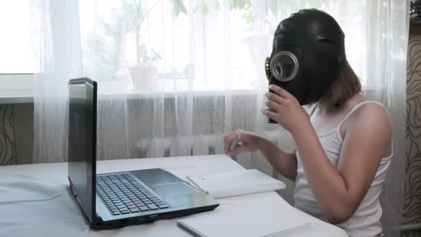 Kleines Mädchen in Gasmaske macht Hausaufgaben mit Laptop, schreibt Notizen in Notizbuch — Stockvideo