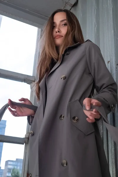 Atraente jovem asiático modelo no cinza trincheira casaco de pé perto da parede ao ar livre — Fotografia de Stock