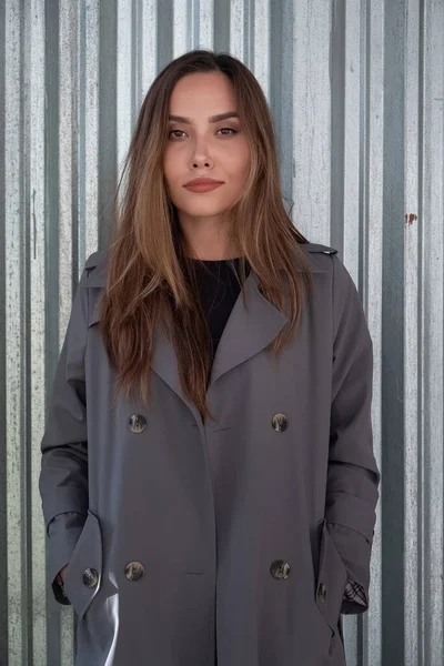 Atraente jovem asiático modelo no cinza trincheira casaco de pé perto de metal cerca — Fotografia de Stock