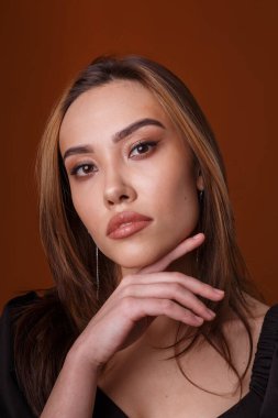 Turuncu arka planda koyu yakalı siyah elbise giyen zarif bir manken.