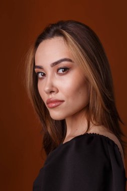 Turuncu arka planda siyah elbise giyen zarif Asyalı genç manken.