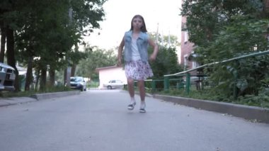 Küçük beyaz etekli kız, asfalt yolda kameraya doğru koşan sandaletler..