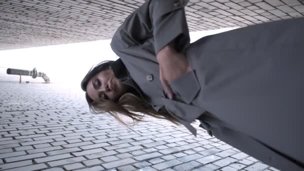 Asiatisk flot model iført skyttegrav frakke stående nær vægge skudt fra lavere punkt – Stock-video