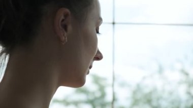 Genç beyaz kadın susuzluğunu gideriyor. Kadın pembe şişeden su içiyor.