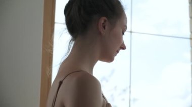 Genç beyaz kadın susuzluğunu gideriyor. Kadın pembe şişeden su içiyor.