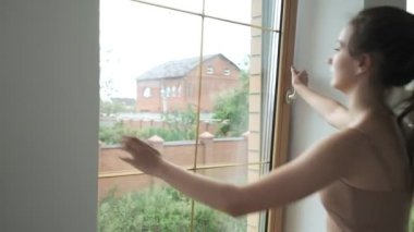 Genç, esmer, atkuyruklu güzel bayan pencereyi kapatıyor, yakın plan.