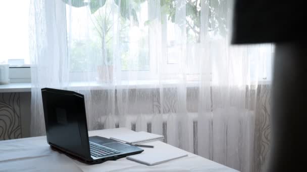 Joven enfocado se sienta a la mesa con el ordenador portátil, se prepara para escribir notas — Vídeos de Stock