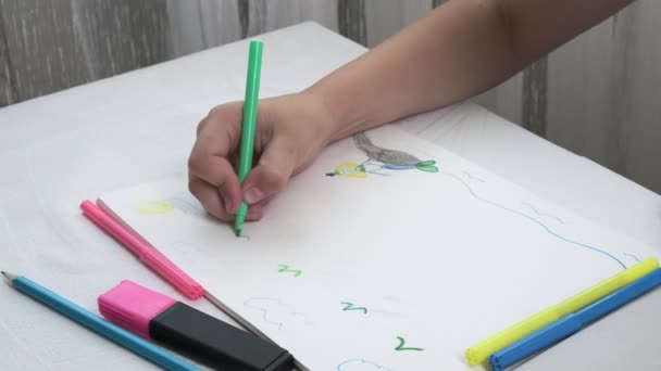 Meisje in gas masker zit aan tafel, tekent illustratie met vilten pennen in album — Stockvideo