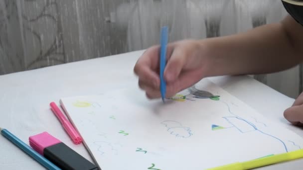 Fille en masque à gaz se trouve à table, dessine illustration avec des stylos en feutre dans l'album — Video