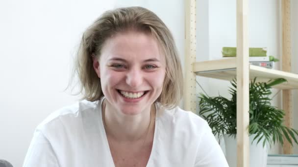 Een jonge blanke vrouw die thuis lacht. Portret van lachende vrouw — Stockvideo