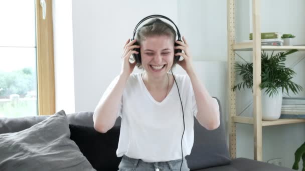 Kulaklıklı genç beyaz kadın evde gülümsüyor. Gülen kadın portresi — Stok video