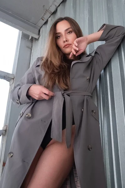 Gri trençkotlu ve açık havada siyah takım elbiseli çekici Asyalı genç bir model.