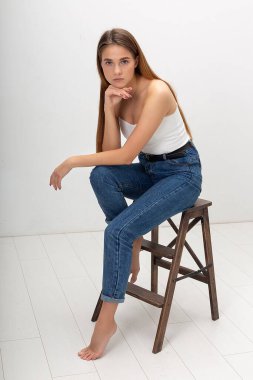 Korse ve kot pantolon giymiş uzun saçlı beyaz güzel bir kadının portresi.