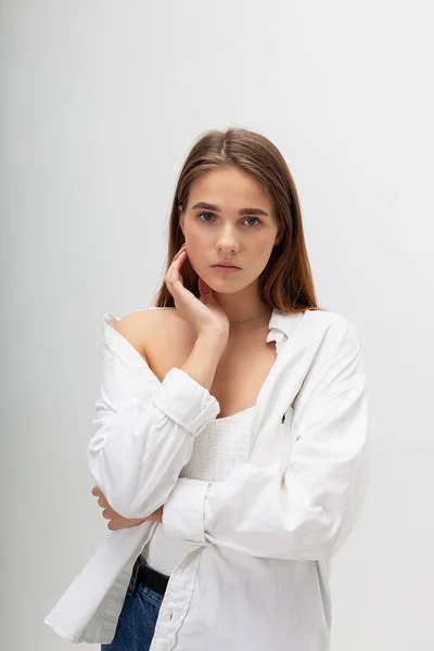 Joven mujer caucásica con pelo largo en camisa y vaqueros azules sobre fondo blanco — Foto de Stock